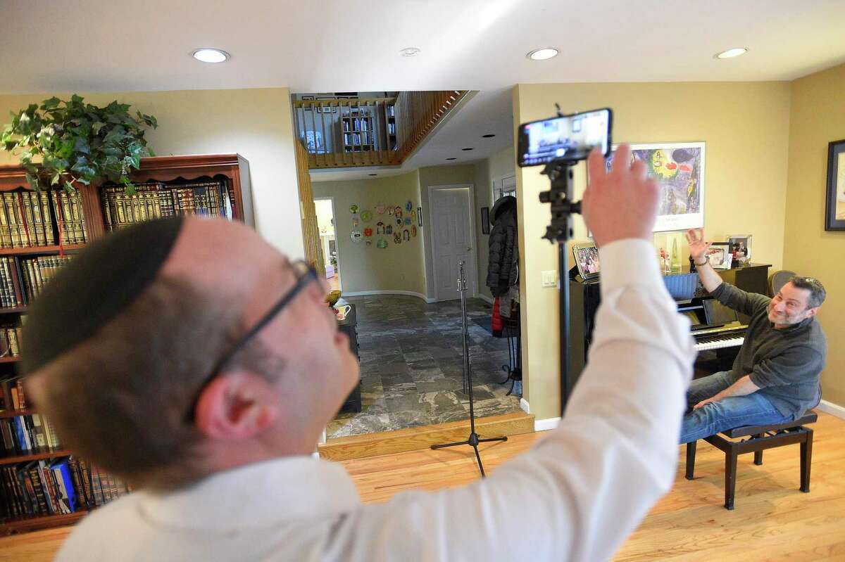 Rabbi Daniel Cohen, foreground, and Jonathan Cahr of Stamford broadcast a Virtual Shabbat service for congregants of Congregation Agudath Sholom via a Facebook Live at the Rabbi's Stamford, Connecticut home on March 13, 2020. The Stamford Synagogue has closed its doors for the next several weeks, canceling all planned events and asking its congregants to self worship and pray, as the nation deals with the COVID-19 Coronavirus Pandemic. The telecast of the service brought approximately 40 viewers with many commenting to thank the Rabbi for providing this unique perspective.