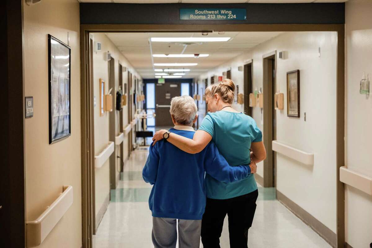 Jen Lingo, right, a registered nurse, walks with a resident of the assisted-living center at Dayton General Hospital in Dayton, Wash.
