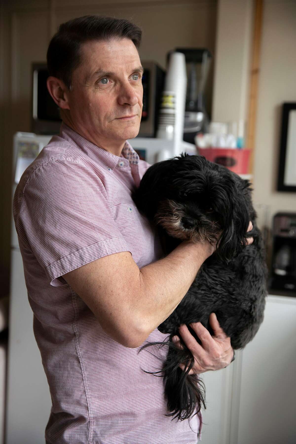 Curtis Bradford with his dog Maggie Mae at his home on Saturday, March 14, 2020, in San Francisco, Calif. Bradford, 55, is HIV positive and part of the population vulnerable to getting sick from the coronavirus. Bradford decided to self isolate on March 6, but has been struggling with the mental and emotional toll of being alone in an SRO without his usual work and community activities.