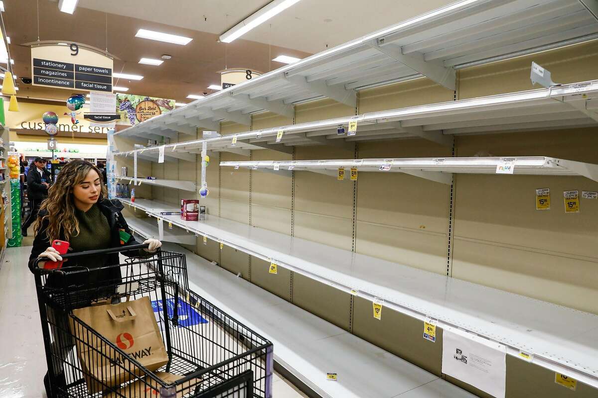 A woman walks past empty shelves at Safeway on 16th Street on Sunday, March 15, 2020 in San Francisco, California. The coronavirus has caused shoppers to stock up on various items like water and toilet paper.