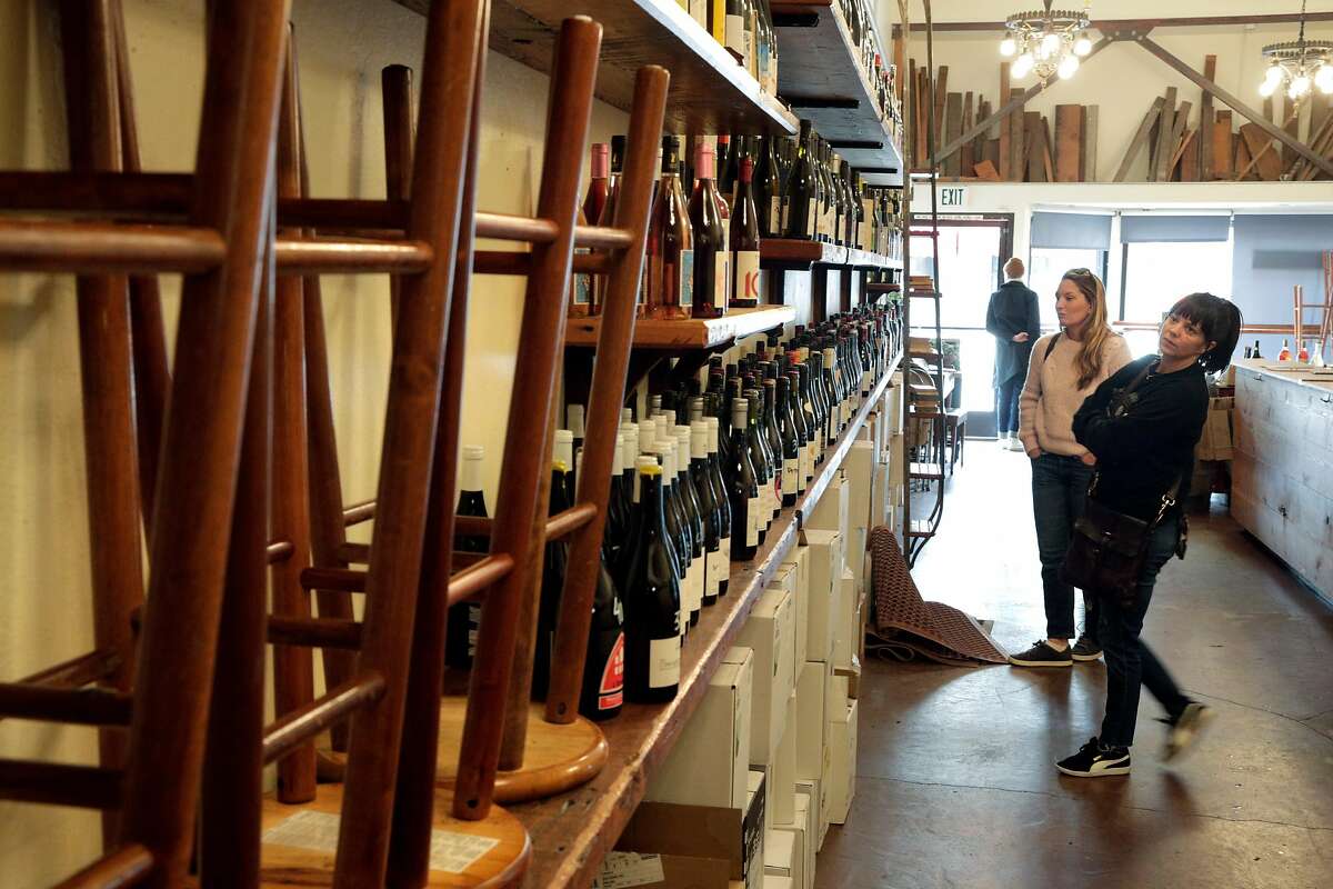 Joey Mazzera, right, and Reba Gray, left, shop wine at Ordinaire Wine Shop and Wine Bar that stopped bar service in Oakland, Calif., on Sunday, March 15, 2020, following an announcement by California Governor Gavin Newsom. The governor’s announcement directs bars, wineries, nightclubs and breweries to close to curtail the spread of the Covid-19 virus, and stopped short of requiring restaurants to do so, but that they should cut seating capacity. Ordinaire it stopping bar service and keeping only retail service, asking customers to not touch the wine bottles, having employees handle the bottles for them.