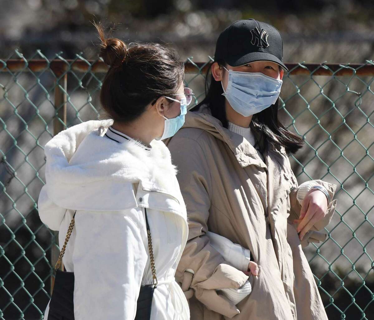 Two women wear masks to protect against the coronavirus as they walk down the street in Stamford on Sunday.