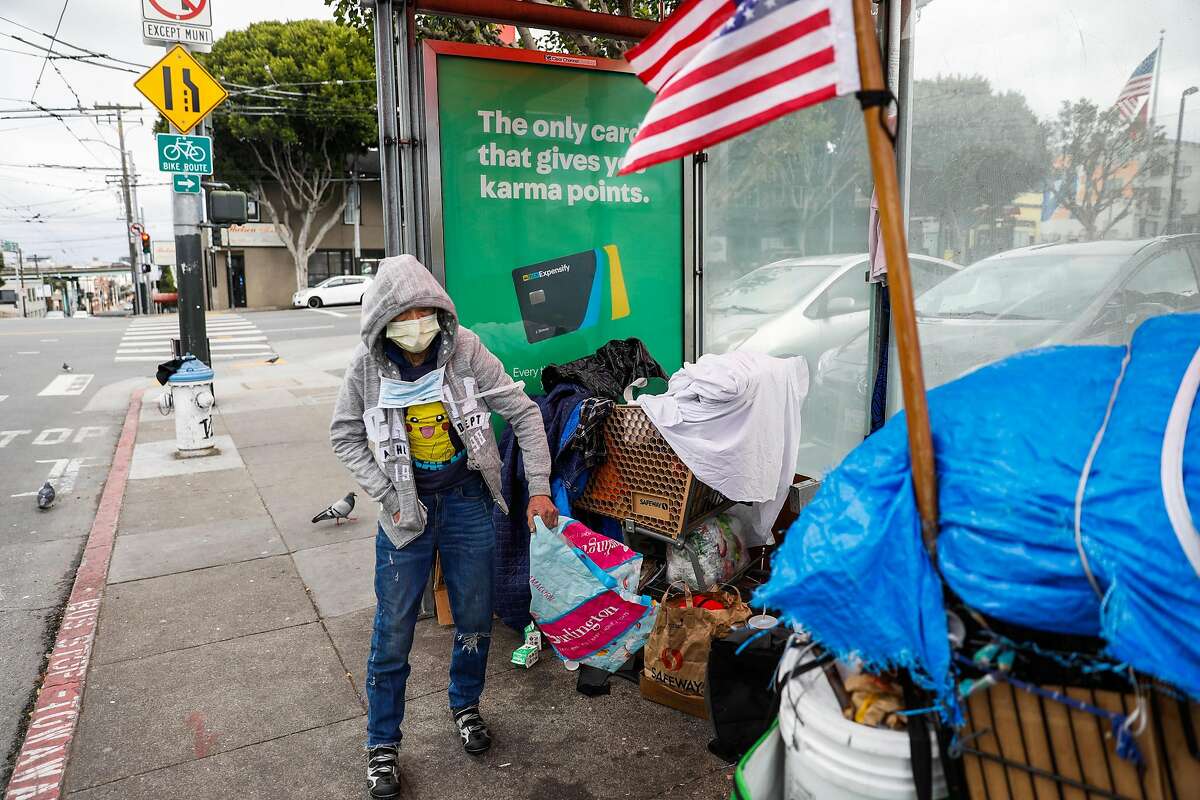 A homeless woman who wished to remain anonymous wears a mask as she prepares her belongings on Sunday, March 15, 2020 in San Francisco, California.