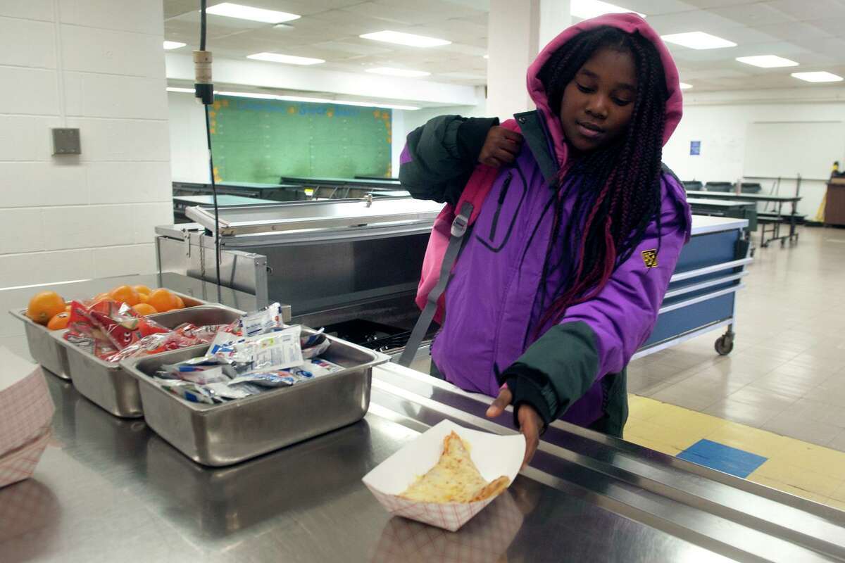 Fifth grader Jeriyah Smith picks up a slice of pizza during a lunchtime visit to the cafeteria at Columbus School, in Bridgeport, Conn. March 16, 2020. Following the closing of schools last week, Bridgeport began serving breakfast and lunch meals to go for city students on Monday.