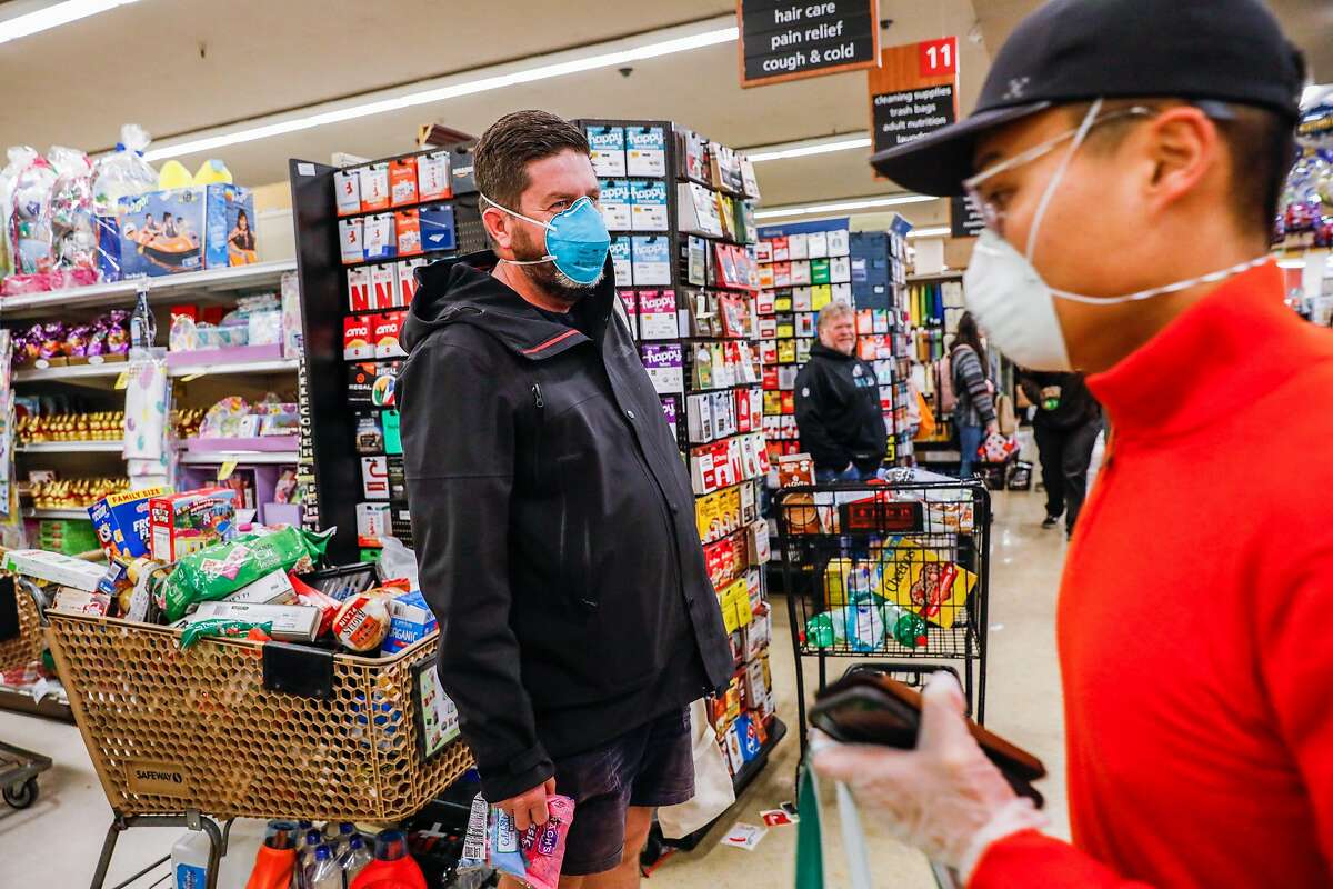 Zach Franzen (left) waits in line to check out at Safeway after Mayor London Breed announced that six Bay Area counties would lockdown non-essential services due to the coronavirus on Monday, March 16, 2020 in San Francisco, California.