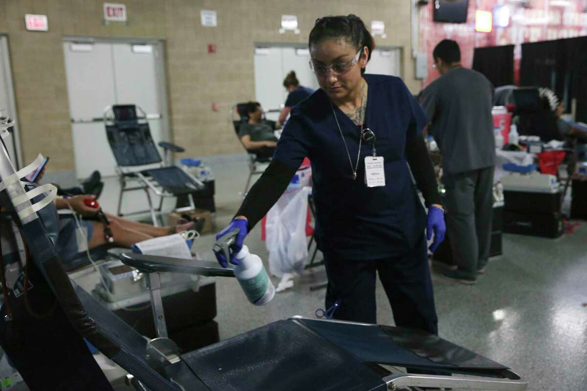 Nataly Chavez Lopez sanitizes a chair for the next donor during a three-day blood drive at the Alamodome.
