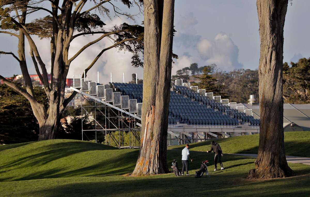 One golfer advises another in front of temporary seating under construction at TPC Harding Park where preparations are underway for the 2020 PGA Championship in San Francisco, Calif., on Monday, March 16, 2020.