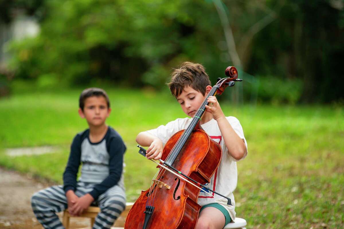 Winnie Weisberg plays his cello from the corner of his street, Tuesday, March 17, 2020, in the Westbury neighborhood of Houston. Parker Elementary School cello teacher Lisa Vosdoganes encouraged students at the HISD music magnet to take to their individual front yards at 10 am Tuesday morning to play together, apart.