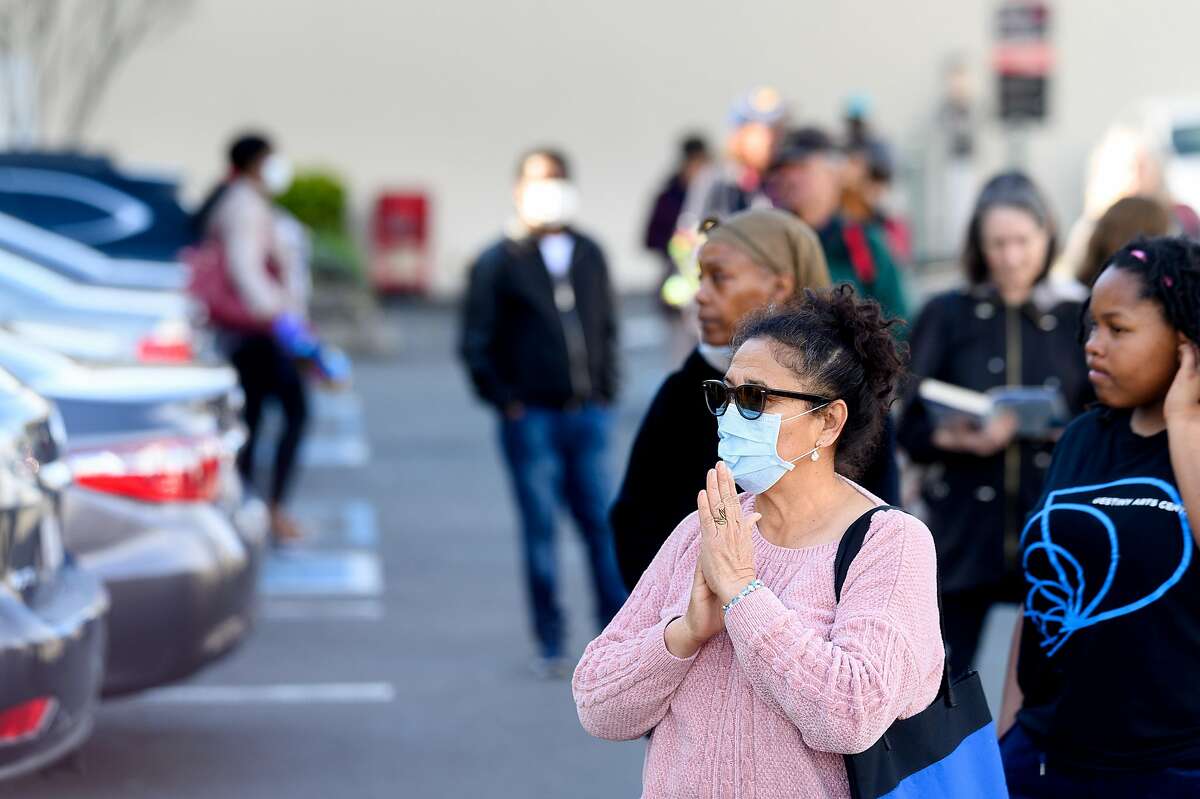 Angela Massella waits in line to buy supplies at Trader Joe's in Oakland, Calif., on Tuesday, March 17, 2020. Massella hoped to buy eggs, milk and paper towels as Alameda County entered its first day of shelter in place orders to slow the spread of coronavirus.