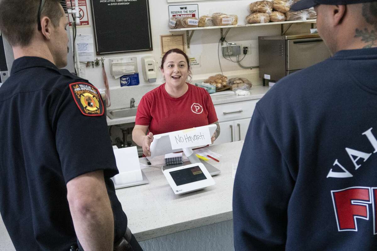 Vallejo Fire Department firefighters Kevin Brown, left, and Capt. Jason Ward, right talk to manager Erica Bostian, center, while picking up lunch at Picnicky's Sandwich Shop in Vallejo on Tuesday.