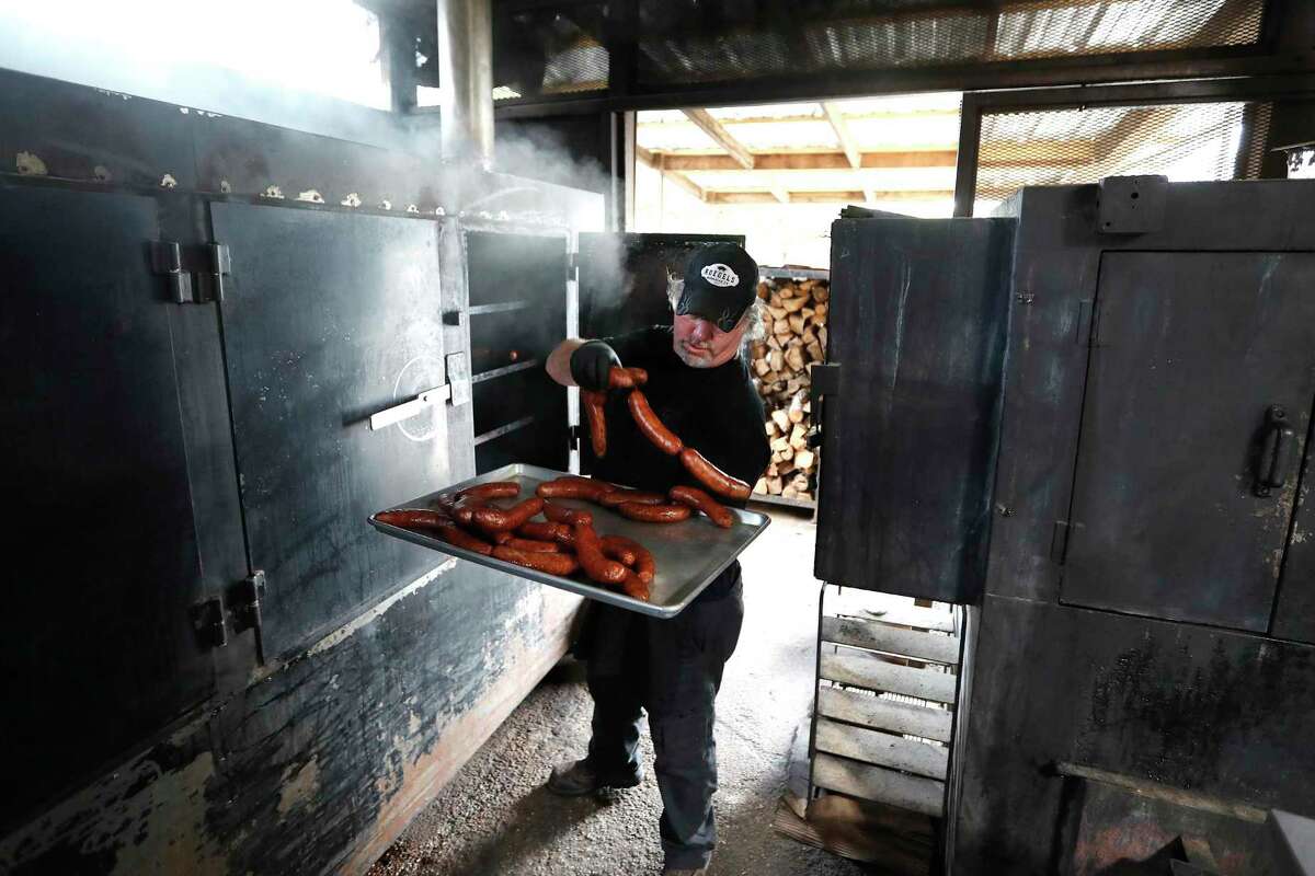 Russell Roegels, owner of Roegels Barbecue Co. at 2223 S. Voss pulls sausages out of the smoker. Roegels is among the Houston restaurant owners who are grappling with ways to stay in business since Harris Country enters 15-days of limiting service to only take-out and pick-up.