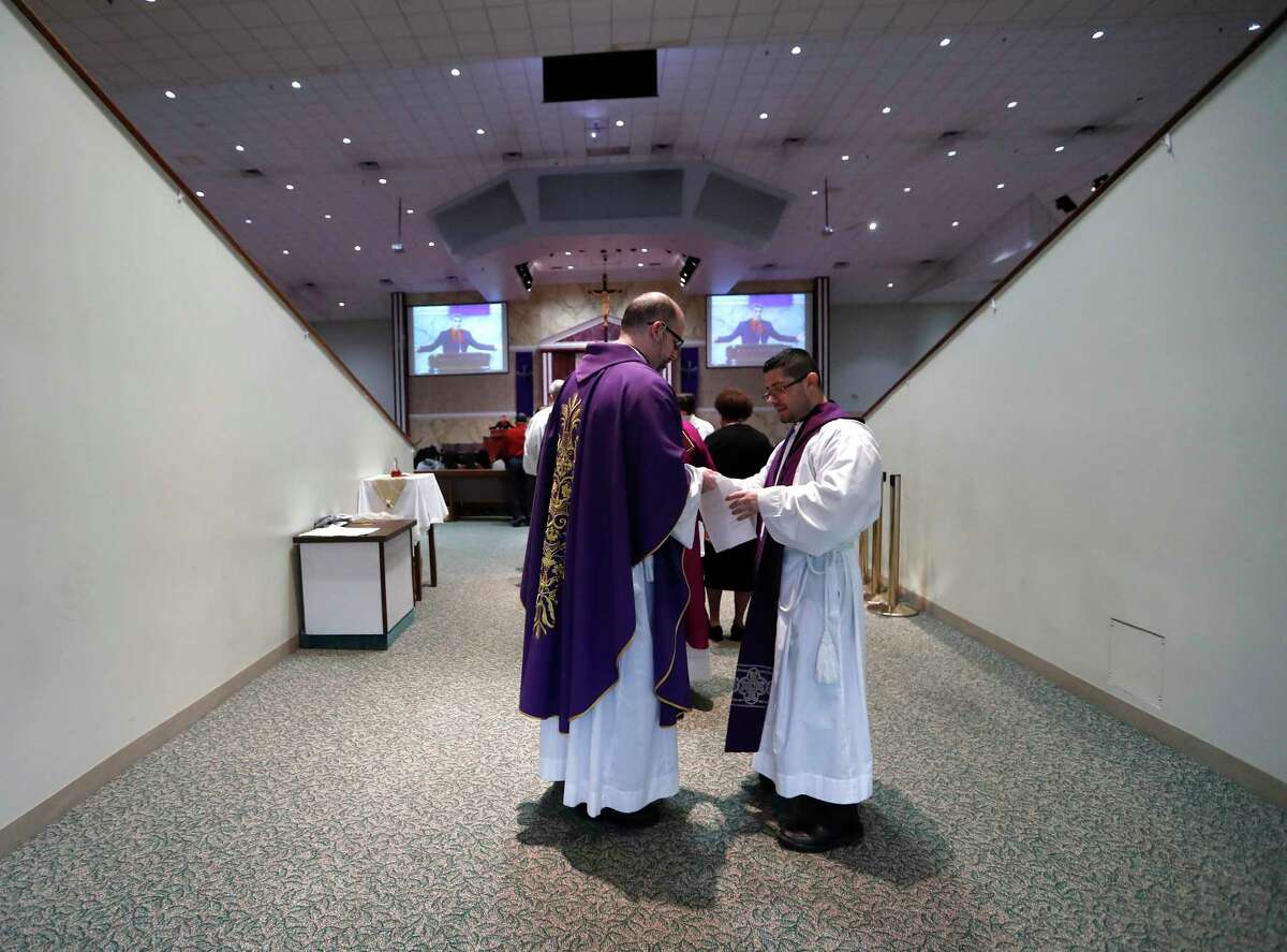 Fr. John Paul Bolger, left, helps Fr. Jorge Alvarado prepare for Sunday's mass at Catholic Charismatic Center 1949 Cullen, in Houston,Sunday, March 15, 2020. The church normally has as many as 1200 parishioners on Sundays, however, many people opted to watch it live-streamed, as fears of being in large groups may have kept people home.