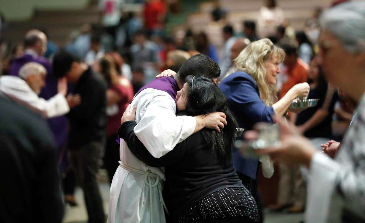 A woman hugs Fr. Jorge Alvarado during communion during Sunday mass at Catholic Charismatic Center 1949 Cullen, in Houston,Sunday, March 15, 2020. The church normally has as many as 1200 parishioners on Sundays, however, many people opted to watch it live-streamed, as fears of being in large groups may have kept people home.