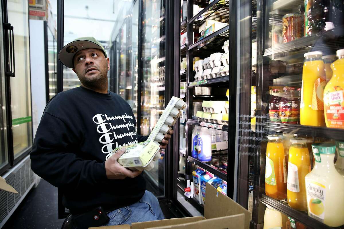 Fahman "Sam" Aloidi, an employee at the Savemore Market, located at 4219 Park Blvd., listens to a customer as he stocks a shelf with eggs on Tuesday, March 17, 2020, in Oakland, Calif. "People are taking it like crazy," Aloidi said. I've never seen it this crazy before. The shelves are empty." The store expects to stock up on toilet paper, hand sanitizer, and antibacterial wipes in a week, if not sooner. Tuesday is the first day of a mandatory three-week lockdown in the San Francisco Bay Area, in an effort to prevent the spread of coronavirus COVID-19.