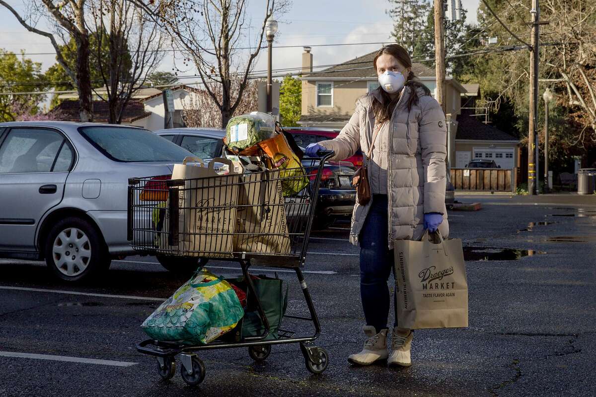 A mother of an infant from San Carlos (no name given) poses for a portrait while wearing a protective mask and gloves after shopping for her groceries from Draeger's Market in Menlo Park, Calif. Tuesday, March 17, 2020. As of Tuesday, six counties in the Bay Area have been ordered to shelter in place in an attempt to prevent the spread of the Coronavirus.