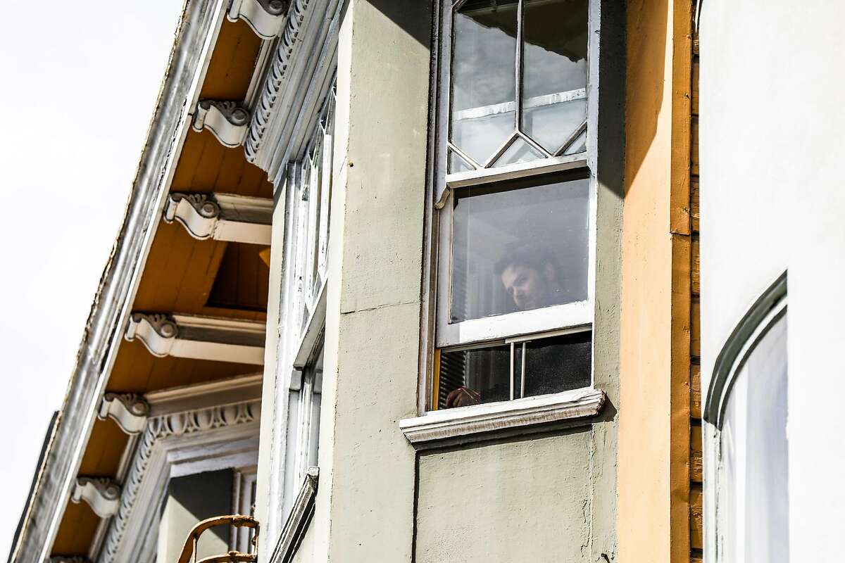 A person is seen in their window on Tuesday, March 17, 2020 in San Francisco, California. The city is on lockdown due to the coronavirus.