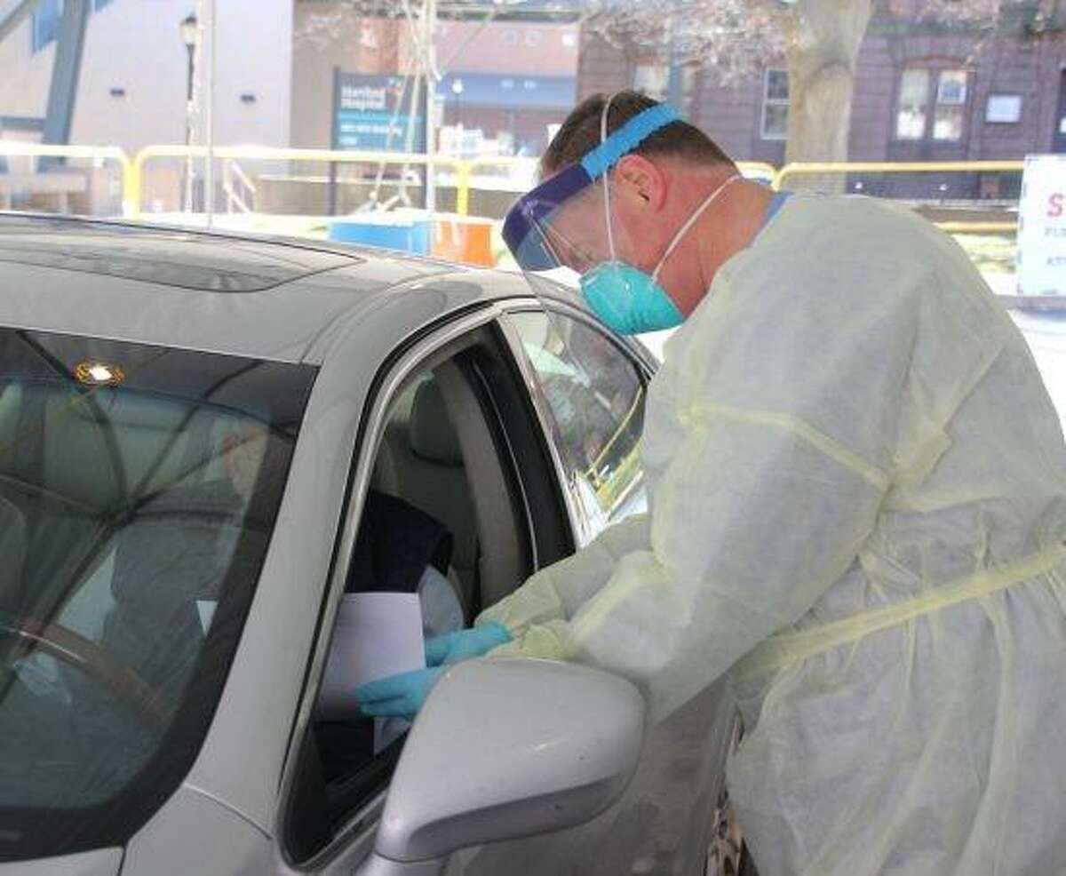 A medical practitioner meets a drive-through patient for coronavirus testing at Hartford Hospital Monday.