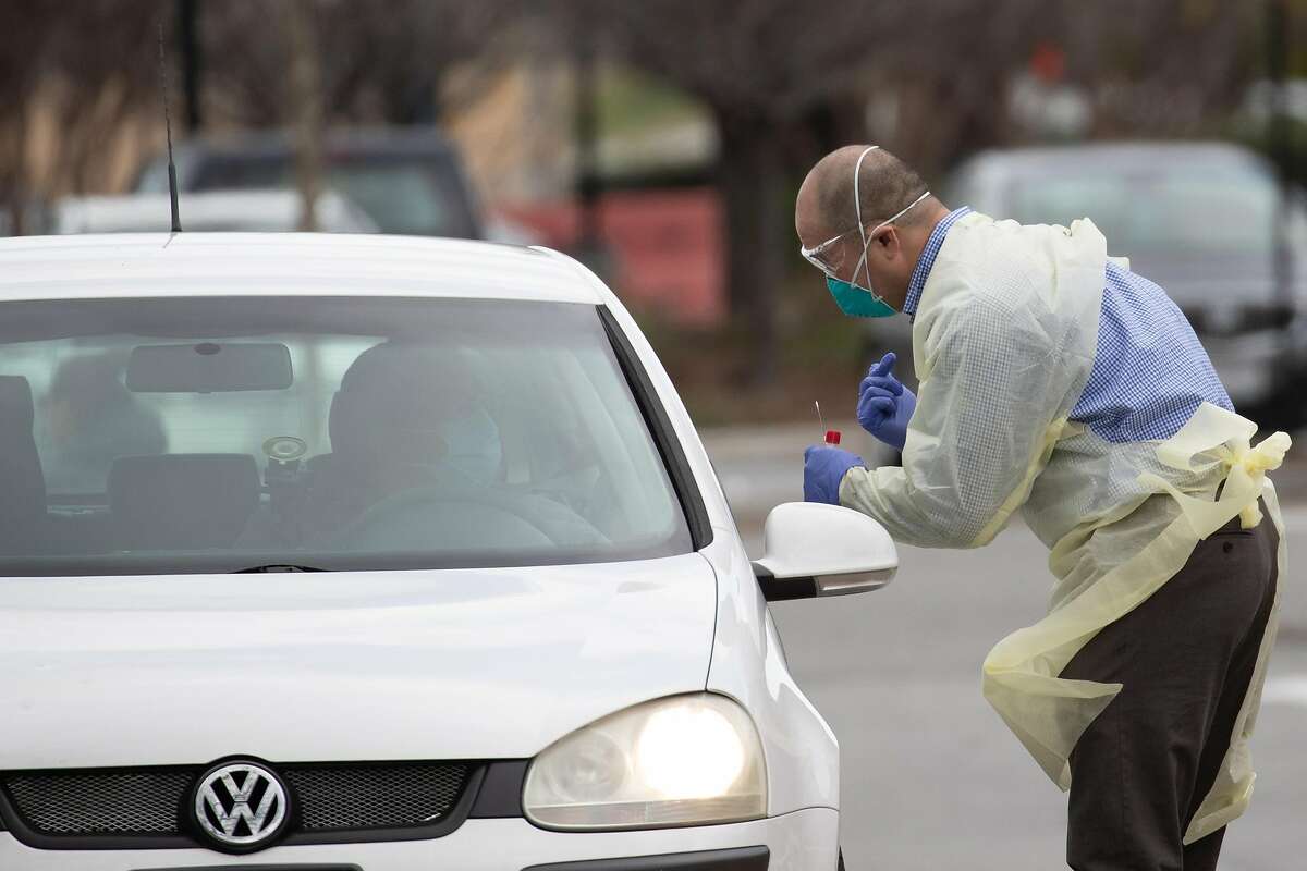 A medical professional prepares to take a saliva sample at a drive-through COVID-19 testing site at Kaiser Permanente - Redwood City Tuesday, March 17, 2020, in Redwood City, Calif.