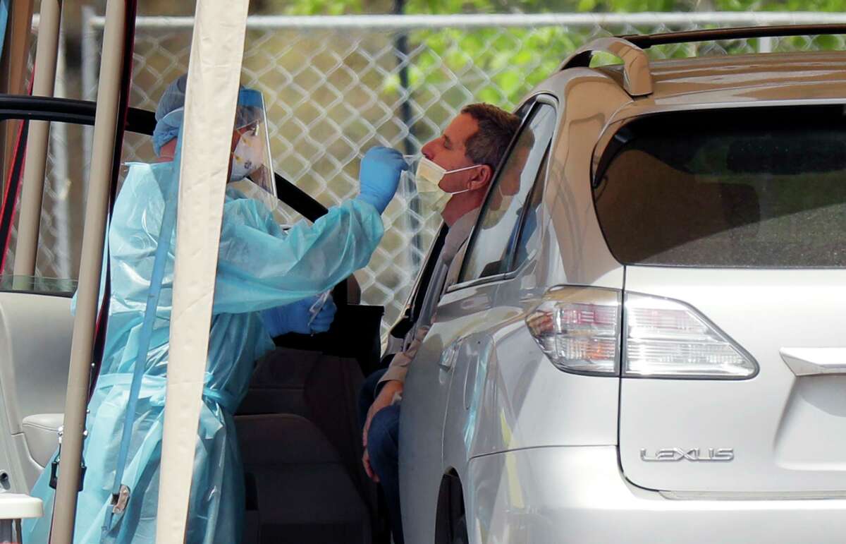 A medical worker tests a person for the coronavirus at a drive-through facility primarily for first responders and medical personnel in San Antonio on Tuesday, March 17, 2020.