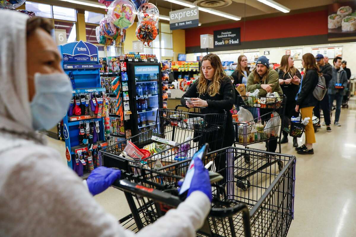 Cassidy Butler (center) and others wait on line at Safeway on 7th Avenue on Tuesday, March 17, 2020 in San Francisco, California. The city is on lockdown due to the coronavirus.