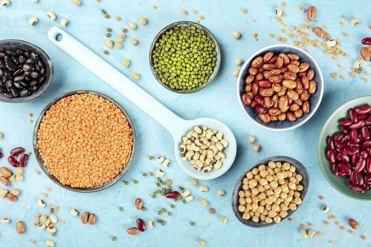 Legumes, shot from the top on a blue background. Vibrant pulses including colorful beans, lentils, chickpeas, a flat lay composition