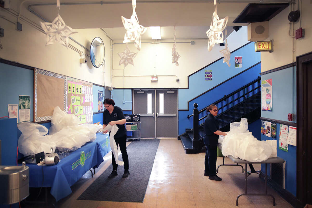 Lisa Faiola, left, and Evangelina Mota prepare meals to distribute to the families of students in need even as classes have been cancelled at Columbus Grade School on March 17, 2020 in Chicago. Illinois schools have been ordered closed to help slow the spread of COVID-19.