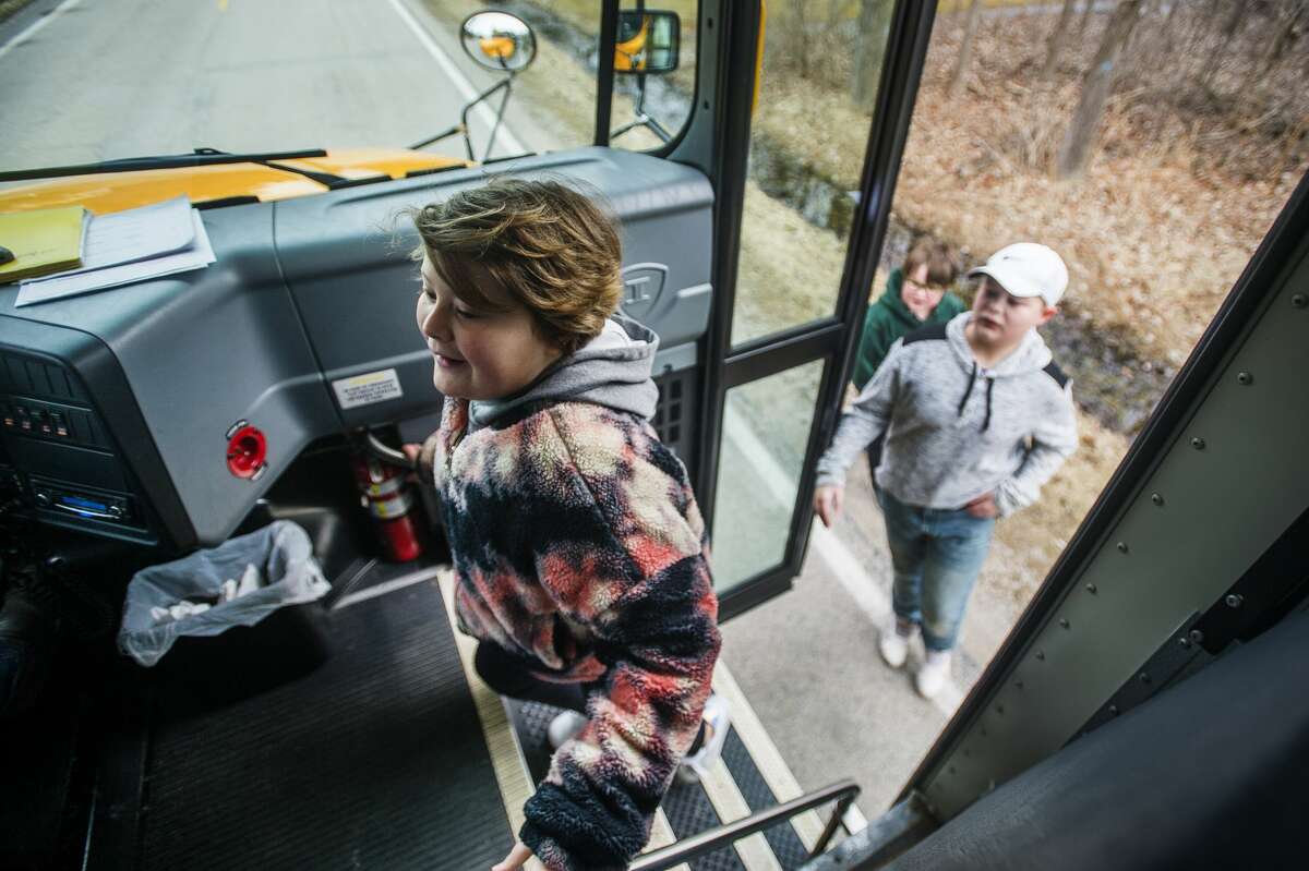 Phoenix Sinclair, 9, followed by Maddox Sinclair, 12, and Jack Spann, 9, bound onto their school bus as their bus driver, Craig Gombosi, delivers meals to Bullock Creek students on his route Wednesday, March 18, 2020. (Katy Kildee/kkildee@mdn.net)