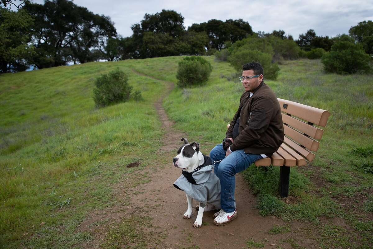 Cash Caris takes a walk with his dog, Mikey, at Quick Silver Park Wednesday, March 18, 2020, in San Jose, Calif. A manager at Peet’s Coffee, he’s concerned about operating safely with the coronavirus.