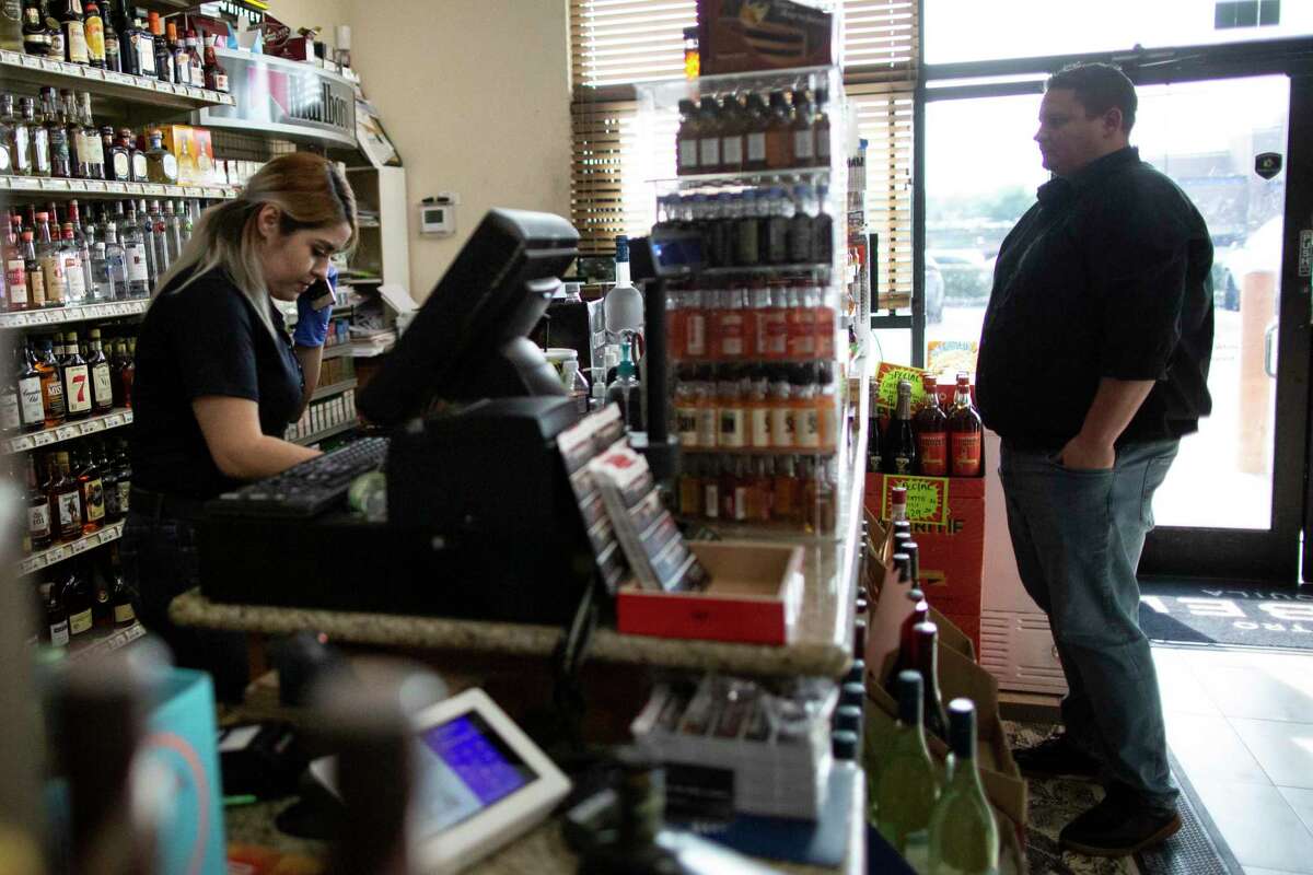 Nancy Ramirez, 24, finishes an order via phone while a customer waits to check out at Premier Fine Wine & Spirits near the Heights are on Wednesday, March 18, 2020, in Houston.
