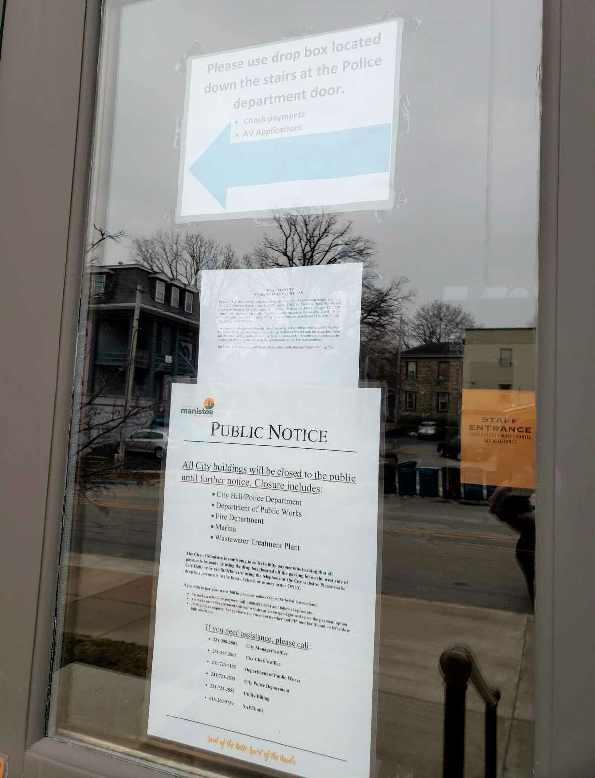 Manistee City Hall's public entrance has notices taped to the window alerting visitors that the city has ceased face-to-face interactions and visits for all city buildings in light of the efforts to curb the coronavirus pandemic. (Arielle Breen/News Advocate)
