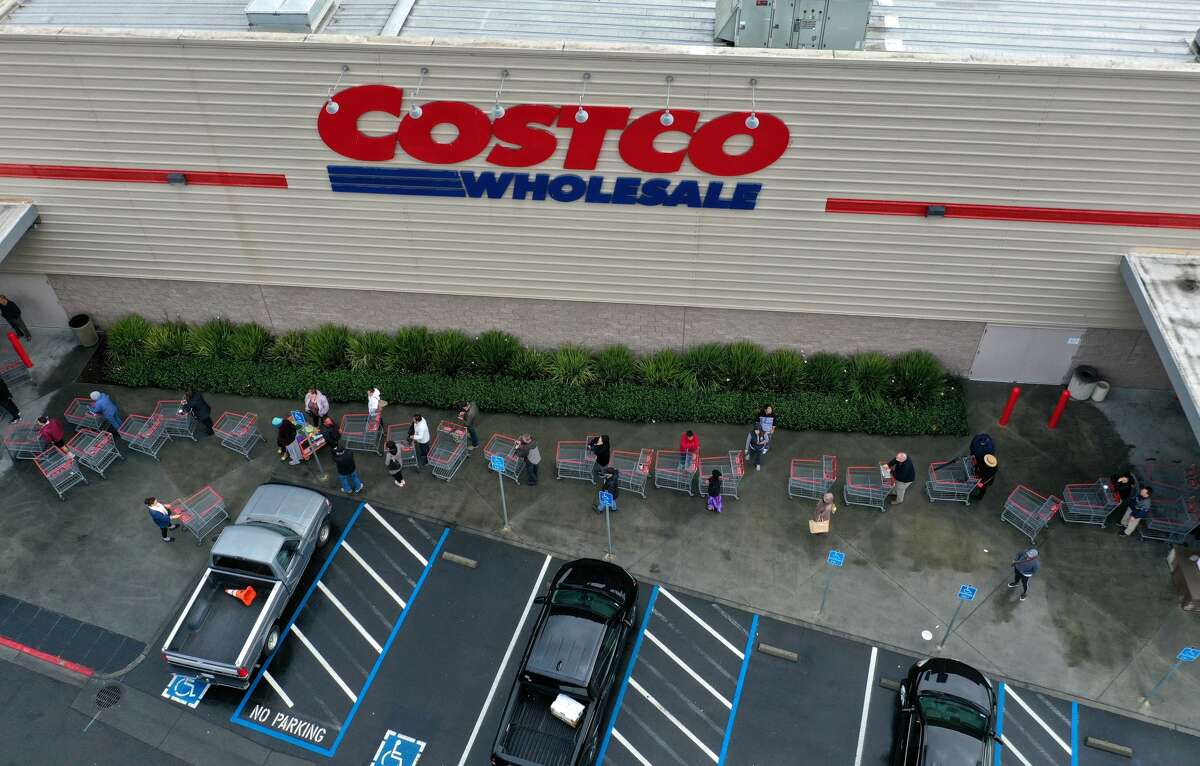 FILE - Hundreds of people line up to enter a Costco store on March 14, 2020 in Novato, California. Some Americans are stocking up on food, toilet paper, water and other items after the World Health Organization (WHO) declared Coronavirus (COVID-19) a pandemic. The company issued new guidelines for customers on April 1, including reduced hours and closures of certain departments.