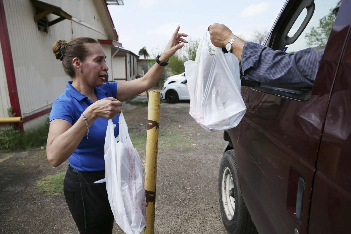 Dora Almanza delivers an order at Paulita's Mexican Restaurant on Jaime Zapata Memorial Highway in Laredo, Texas, Wednesday, March 18, 2020. The City of Laredo issued a lockdown of in response to the coronavirus threat on Tuesday. The order goes into effect at midnight Wednesday and will extend for 14 days. It prohibits the gathering of 10 or more persons and closes malls, entertainment centers, fitness centers and banquet halls. It allows restaurants to open only with drive-thru, delivery or take out service. Essential businesses like medical facilities, veterinarian and grocery establishments are allowed. Offices spaces and places of employment can remain open as long the 10-person rule is followed. Violation of the carries a fine that ranges from $50 to $2,000. The Laredo Police Department will enforce the order. Paulitaâs owner Jorge Santa Anna said that he would try out the takeout option but after seeing a drop in business starting on Tuesday, he thinks he'll have to close for the duration of the order.