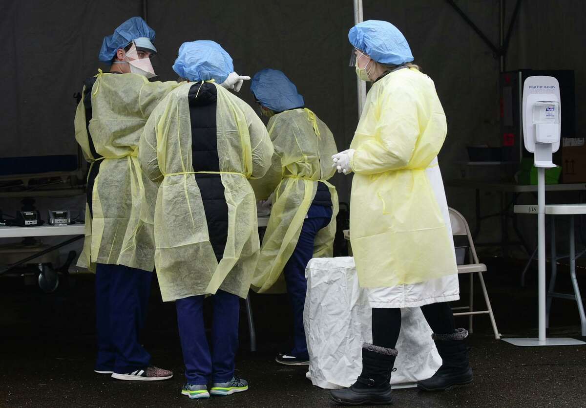 Hospital workers in Personal Protective Equipment collect samples for coronavirus testing at a drive-up faciltiy in the parking lot at Norwalk Hospital Thursday, March 19, 2020, in Norwalk, Conn. Testing is by appointment only with a doctors referral.