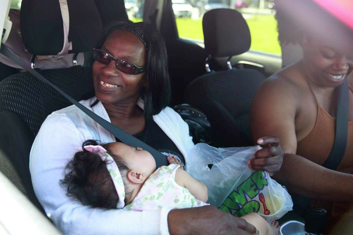 Brenda Dennis, left, holds baby De’Jonae Roseado with Christina Dennis, as they receive a free meal at Dillard High School amid the coronavirus outbreak and school closings on Monday, March 16, 2020, in Fort Lauderdale, Fla.