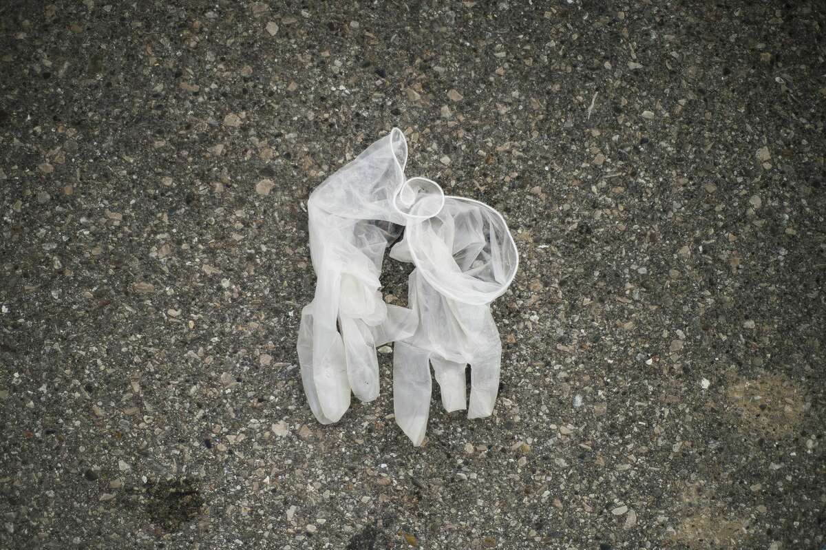 A pair of latex gloves are left on the ground in the Meijer parking lot Thursday, March 19, 2020 in Midland. (Katy Kildee/kkildee@mdn.net)