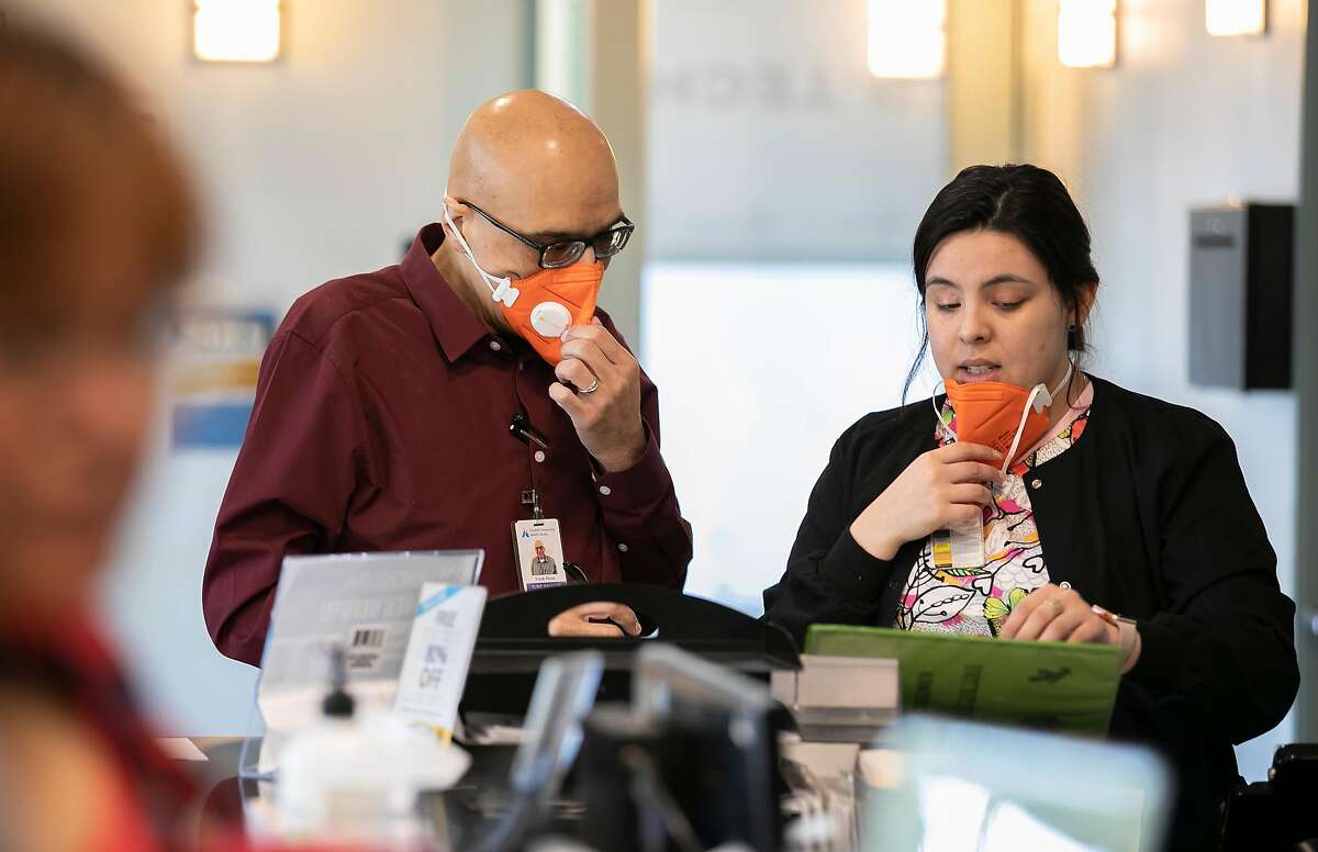 Wearing N95 face masks, from left to right, Clinic Manager Frank Perez and Back Medical Assistant Ericka Salcido confer at the front desk of the Foothill Community Health Center on Monday, Feb. 10, 2020 in San Jose, Calif.