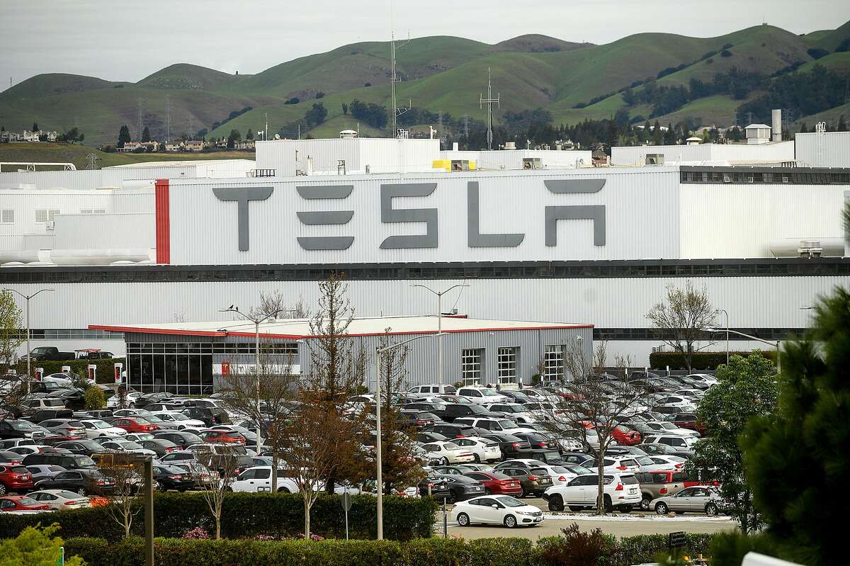 Cars line a parking lot at Tesla's Fremont, Calif., factory on Wednesday, March 18, 2020. The facility remains open despite Alameda County shelter-in-place orders to limit spread of the coronavirus.