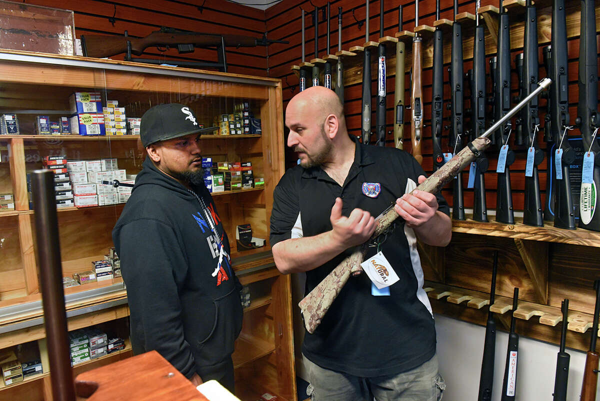 Craig Serafini, owner of Upstate Guns & Ammo, right, shows Kevin Atchana how to use the bolt action rifle that his is thinking of buying at Serafini's gun store on Thursday, March 19, 2020 in Schenectady, N.Y. (Lori Van Buren/Times Union)