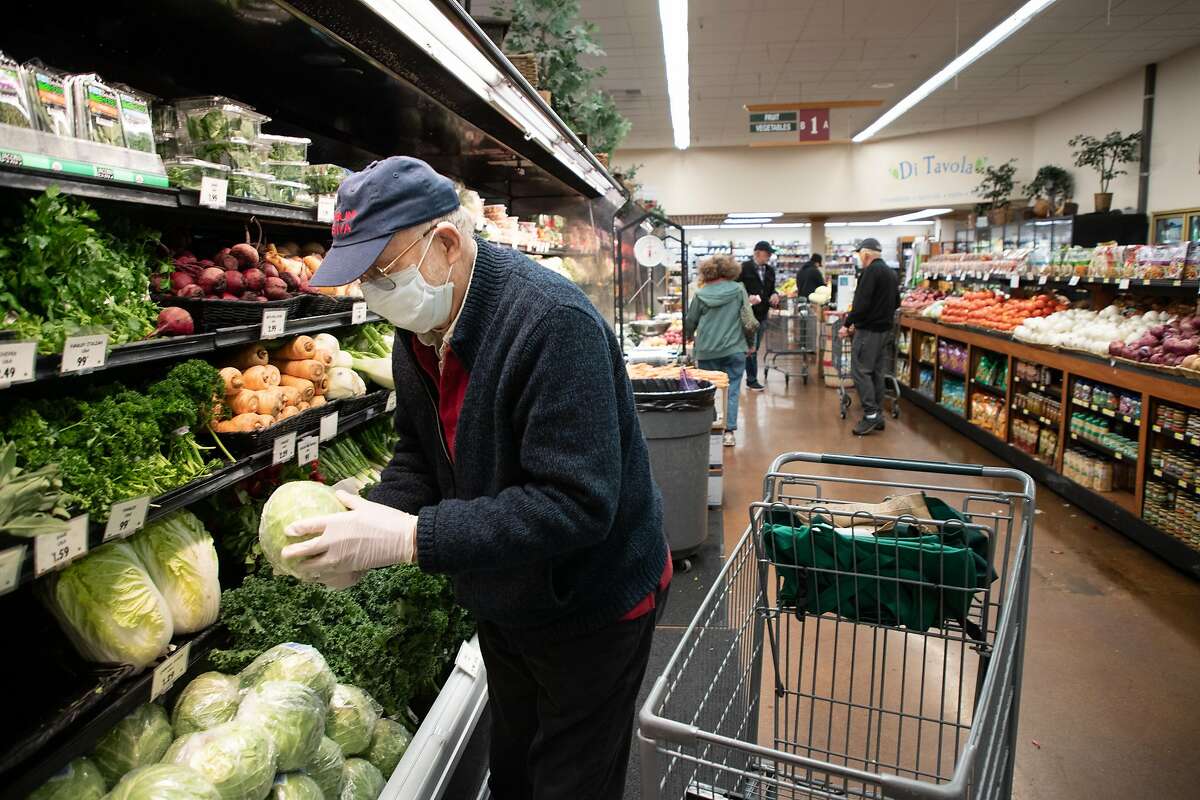 Rene Azigdor, 85, of San Jose, picks up a head of cabbage as he shops at Zanotto�s Willow Glen Market Thursday, March 19, 2020, in San Jose, Calif. The store is open only to seniors from 8 - 9 a.m.