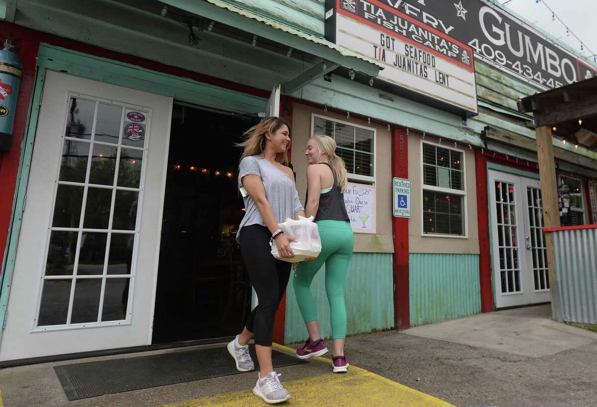 Maddie Allen holds the door for Katherine McAlee as they and friend Tripp Daleo (not pictured) carry out their to-go order at the Tia Juanita's Fish Camp in Beaumont on the first day of area restaurant and bar closures. Photo taken Thursday, March 19, 2020 Kim Brent/The Enterprise