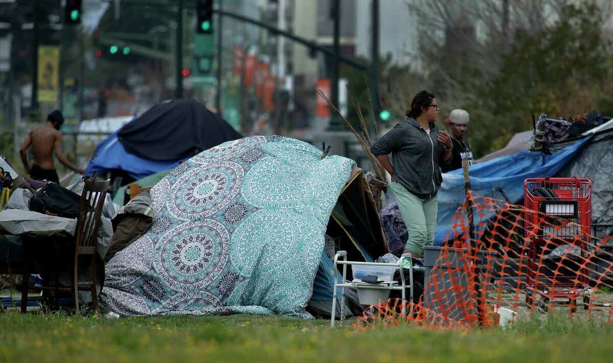 People are seen in a homeless encampment on Thursday, March 19, 2020, in Oakland, Calif. California Gov. Gavin Newsom has authorized $150 million in emergency funding to protect homeless people in California from the spread of COVID-19. $100 million will go to local governments for shelter support and emergency housing, while the remaining $50 million will be for purchasing travel trailers and lease rooms in hotels, motels and other facilities to provide places for the homeless to self-isolate. (AP Photo/Ben Margot)