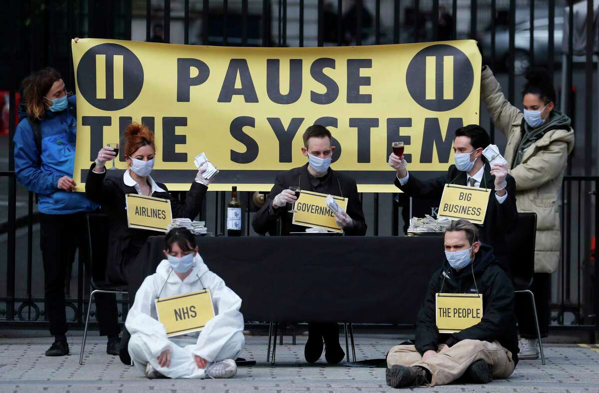 Members of the group 'Pause the System' protest in front of the entrance to Downing Street in London, Friday, March 20, 2020. For most people, the new coronavirus causes only mild or moderate symptoms, such as fever and cough. For some, especially older adults and people with existing health problems, it can cause more severe illness, including pneumonia.