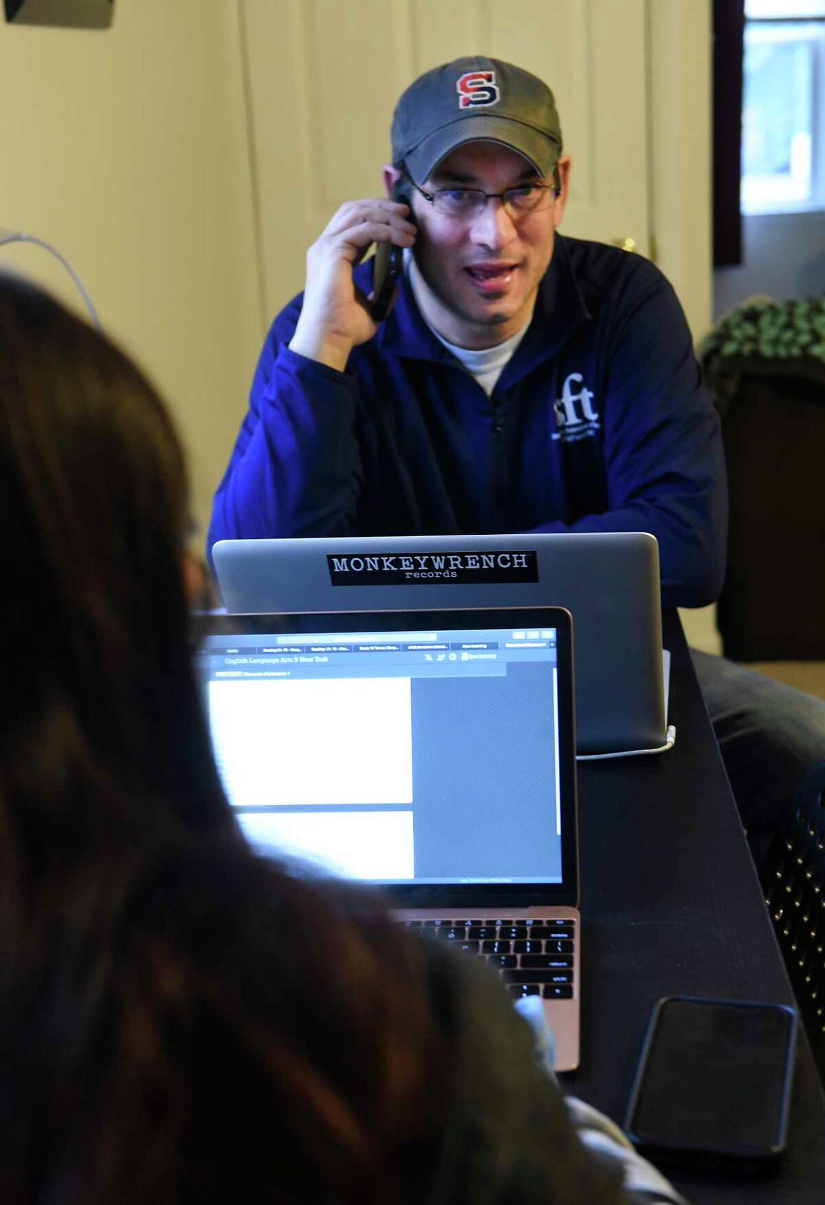 Schenectady High School U.S. history teacher Mike Silvestri calls his students who he sees are not logged on to Google classroom at his home on Friday, March 20, 2020 in Rensselaer, N.Y. Silvestri's 14-year-old daughter Zoe, a freshman at Albany High School, is seen working on a paper for school. (Lori Van Buren/Times Union)
