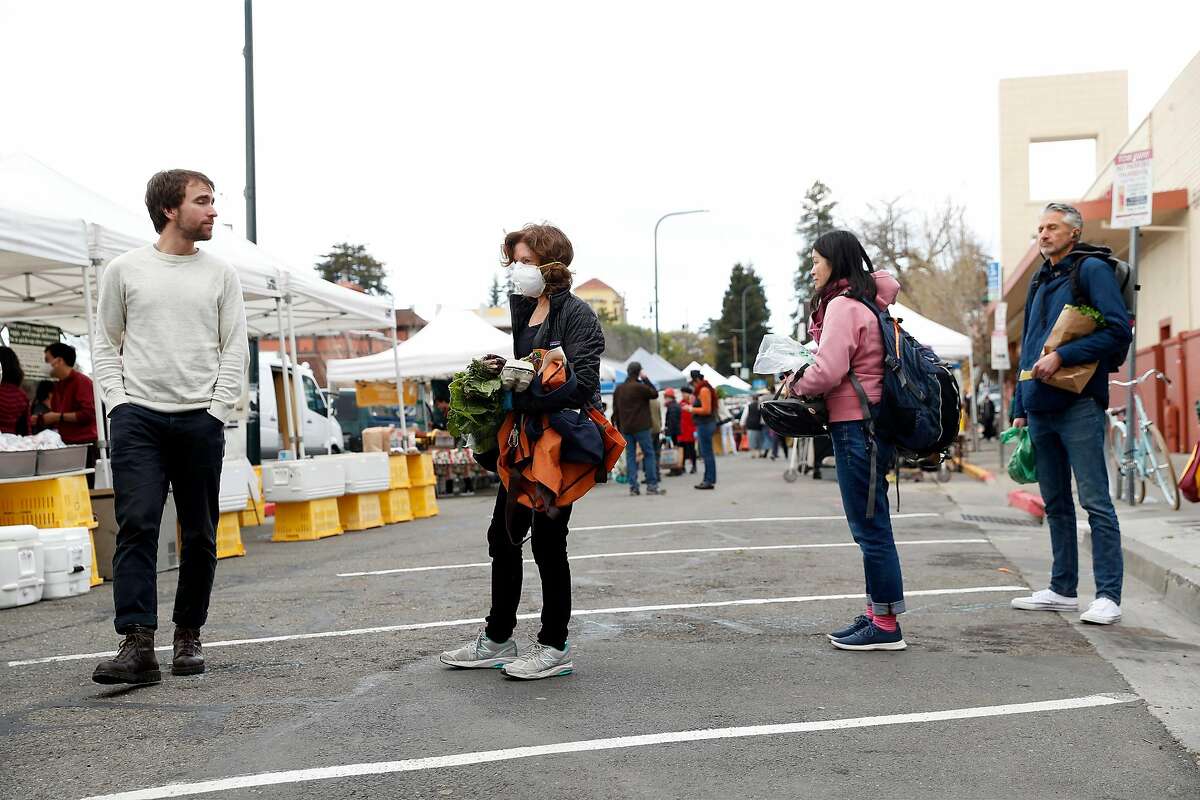 Shoppers adhere to social distancing guidelines while waiting in line at the Berkeley Farmers Market on Shattuck Avenue in Berkeley, Calif., on Wednesday, March 19, 2020.
