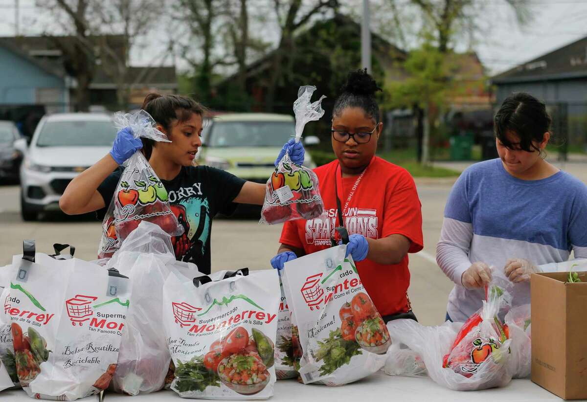 In this March 16 file photo, from left to right, Savanna Ventura, Lillian Stephenson and Amanda Silva put together bags of food for families to pick up at Houston ISD’s Milby High School. HISD officials suspended food distribution at the district’s campuses last week, citing safety concerns, but they plan to restart Monday, Interim Superintendent Grenita Lathan said.