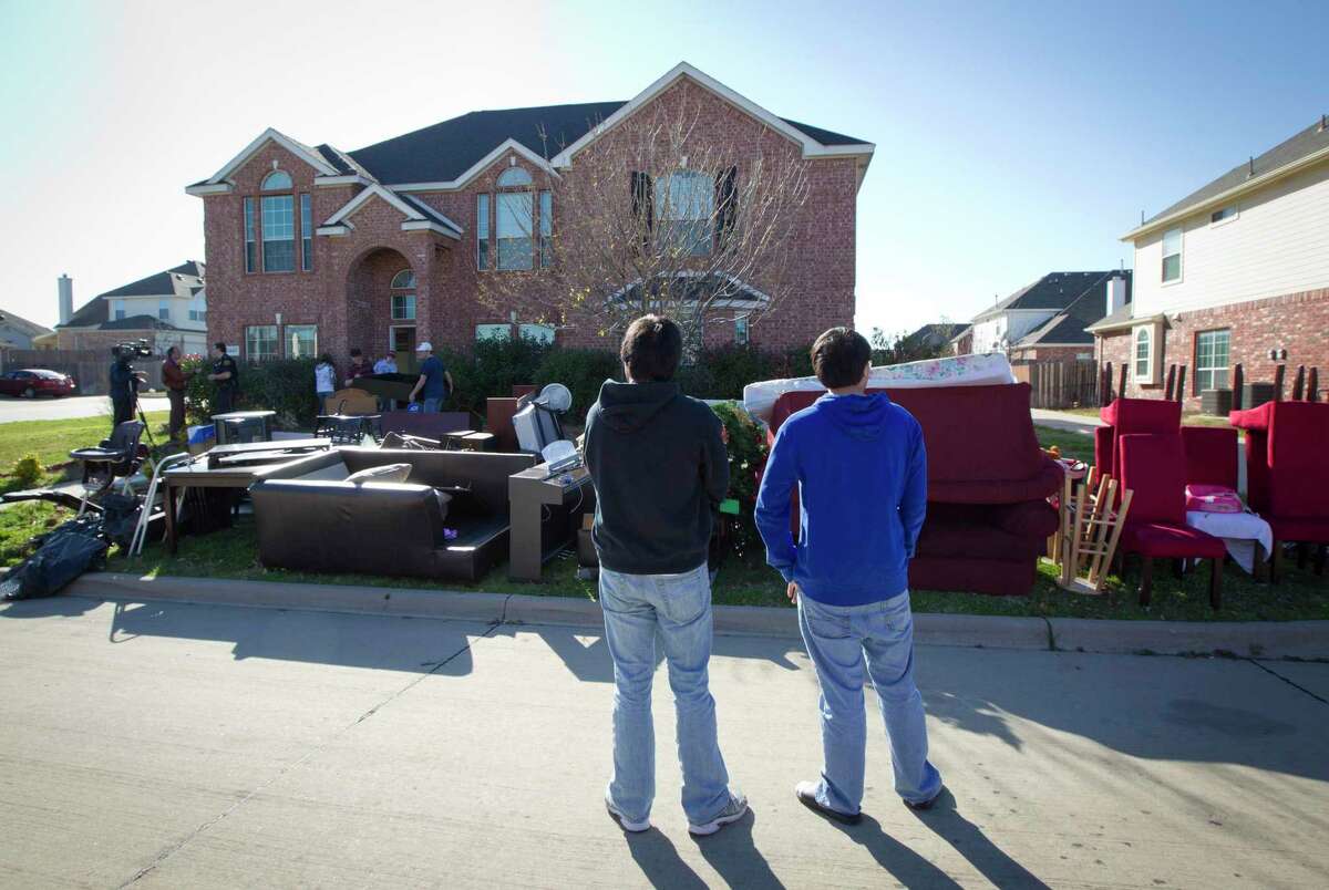 In this Dec. 27, 2011 photo, neighbors watch as all the possessions that squatters had moved into a home in Mansfield, Texas were carried to the curb. They were evicted in November. Nine people in Tarrant County have been indicted on charges related to unlawful trespassing or possession of vacant homes, the Fort Worth Star-Telegram reported. (AP Photo/Star-Telegram, Joyce Marshall)