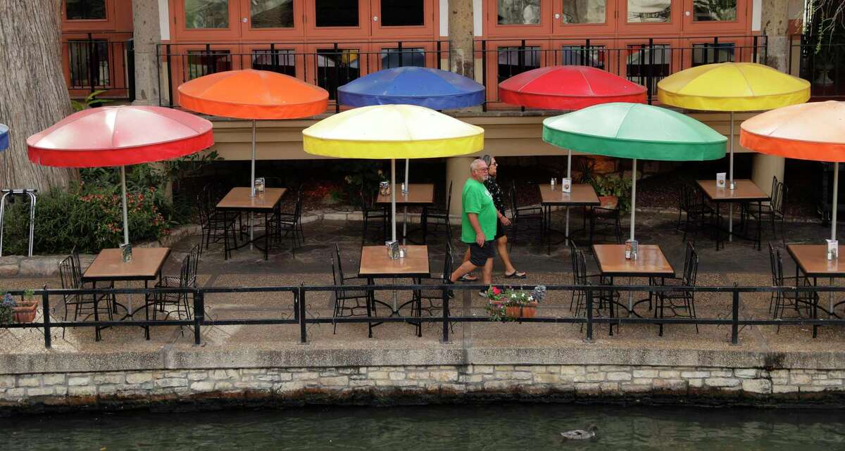 Visitors walk past a restaurant on the River Walk, Monday, March 16, 2020, in San Antonio. The Centers for Disease Control and Prevention is urging people across the U.S. to cancel or postpone events with 50 or more attendees for the next eight weeks to try to contain the fast-moving coronavirus pandemic. (AP Photo/Eric Gay)