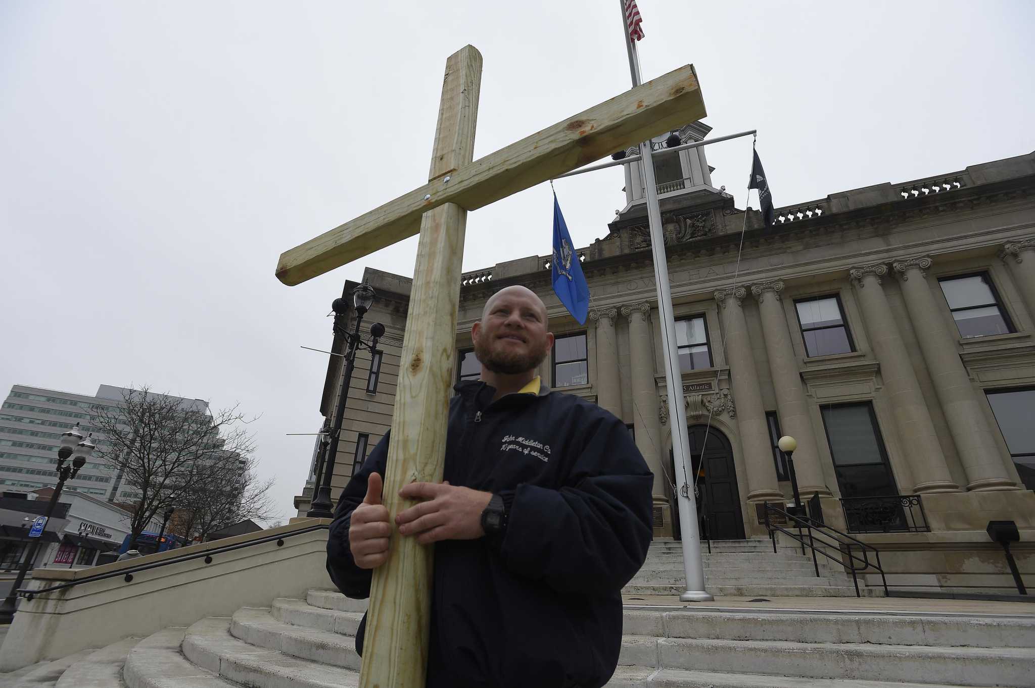 See a reverend who is carrying a wooden cross to spread peace
