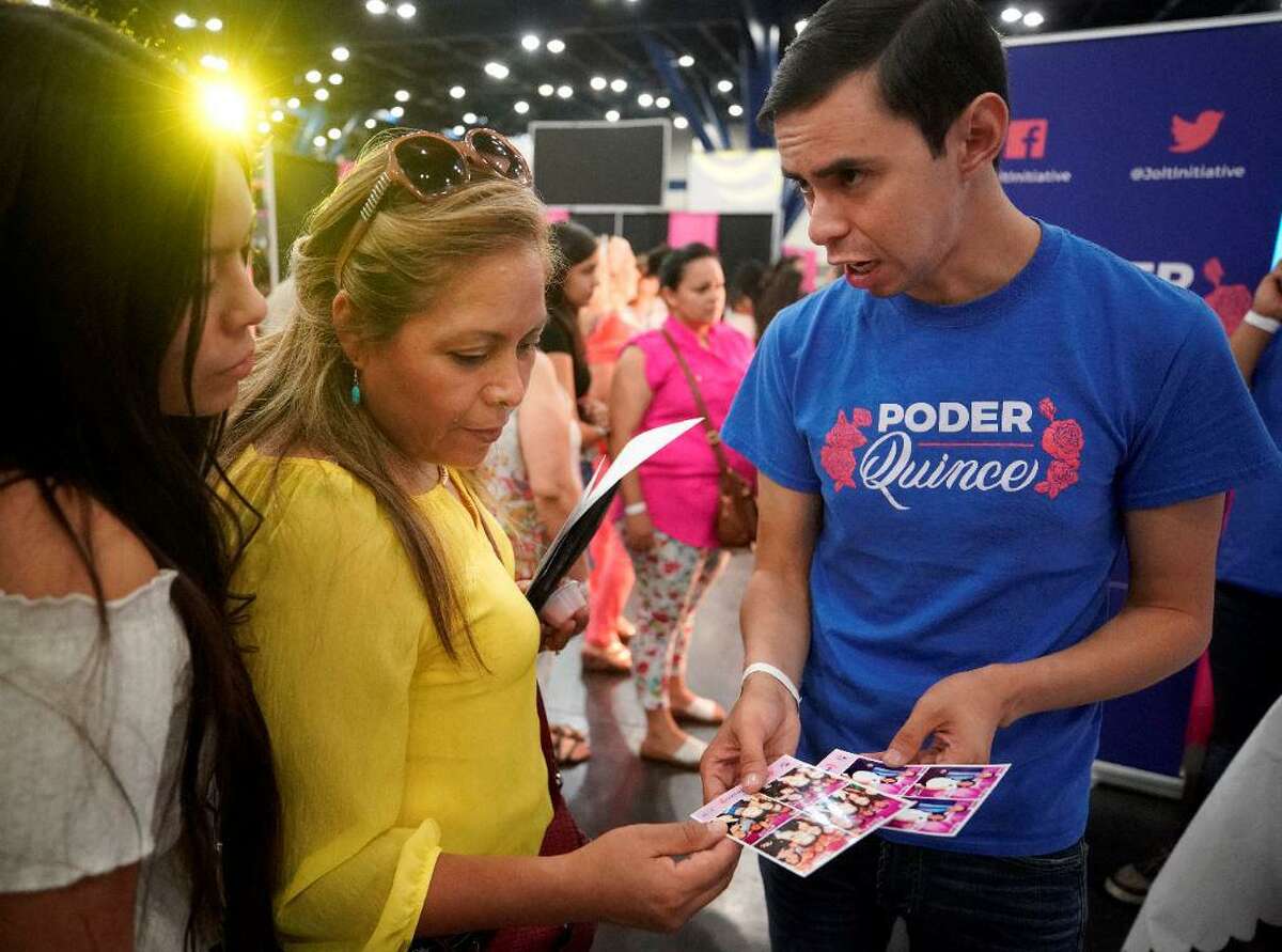 Julie Tovar, 16, and her mother, Carina Tovar, talk with Antonio Arellano, interim excutive director, right, at the Poder Quince booth during the Quince Expo at the George R. Brown Convention Center Sunday, Aug. 4, 2019, in Houston.  Poder Quince is a voter registration drive by Jolt Initiative to increase Latino voter turnout. The group provides a free photobooth at the quinceañera and conducts onsite voter registration during the party.