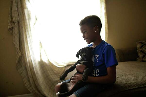 Marquese Jeffries-Johnson, 9, plays with the family’s puppy on Wednesday. The family has no internet connection after being turned away by a Spectrum representative because it owes money from a previous connection. As schools switch to online learning, San Antonio’s digital divide is widening.